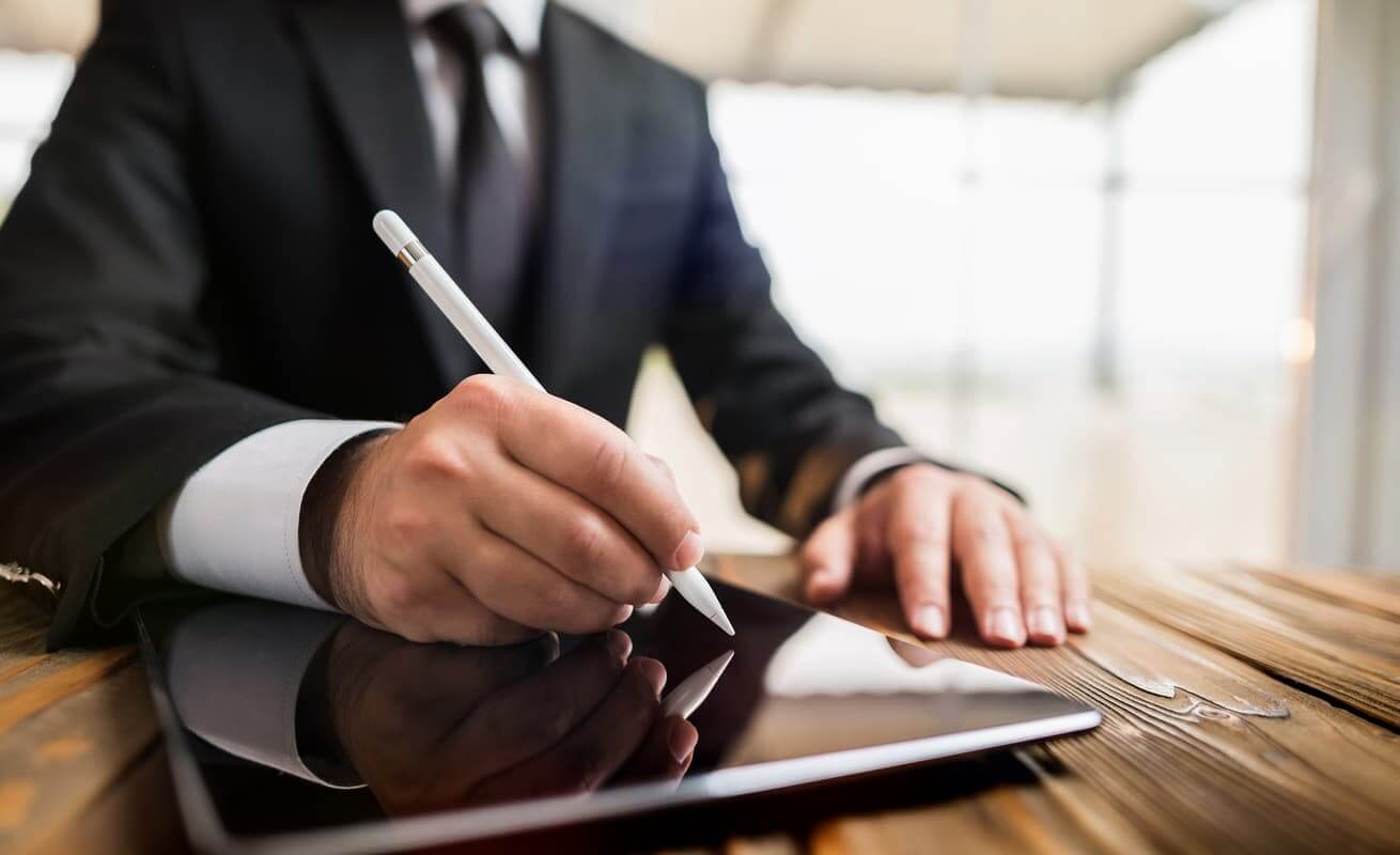 A businessman is using his tablet to sign documents
